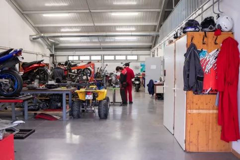 Ateliers des classes de CAP maintenance des véhicules, avec 2 élèves au loin et des véhicules