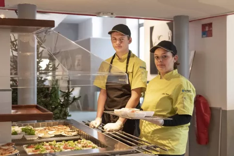 Deux jeunes en train de dresser la table des entrées dans le self