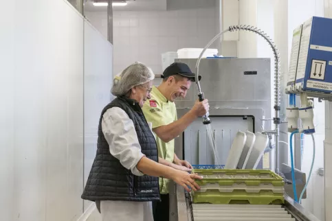 Un jeune et une aide cuisine en train de faire la plonge dans la cuisine