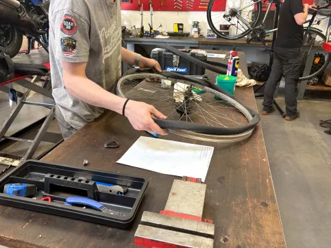 Un jeune en train de manipuler une roue de vélo