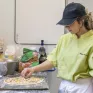 Jeune fille en tenue professionnelle en train de cuisiner une pizza 
